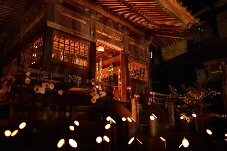 夜の黒川温泉で竹あかりに照らされるお堂と奉納された入湯手形