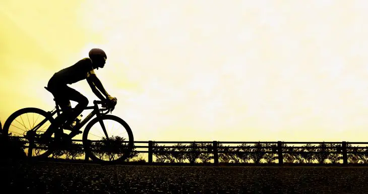 夕空を背景にロードバイクで走るサイクリストのシルエット