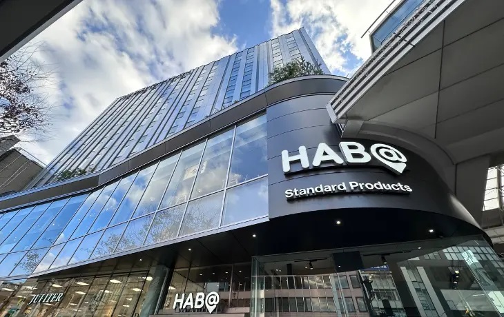 熊本市の商業施設「HAB@(ハブアット)」の外観と青空を背景にしたロゴ看板