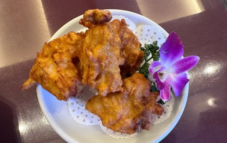福岡「華風 福寿飯店」の一品料理、サクサクに揚がった大ぶりの鶏の唐揚げとお花添え。