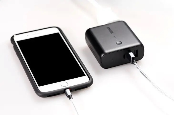 白い背景でスマートフォンにケーブルを接続し、充電中のモバイルバッテリー。