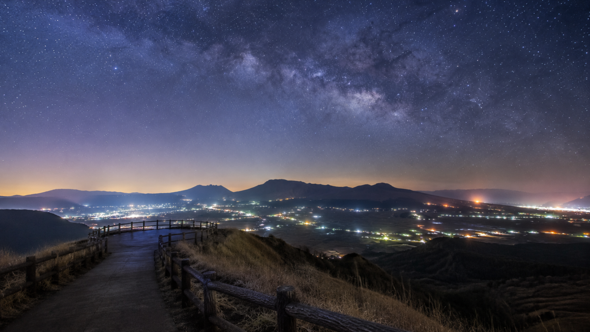 大観峰から望む阿蘇谷の夜景と星空のイメージ